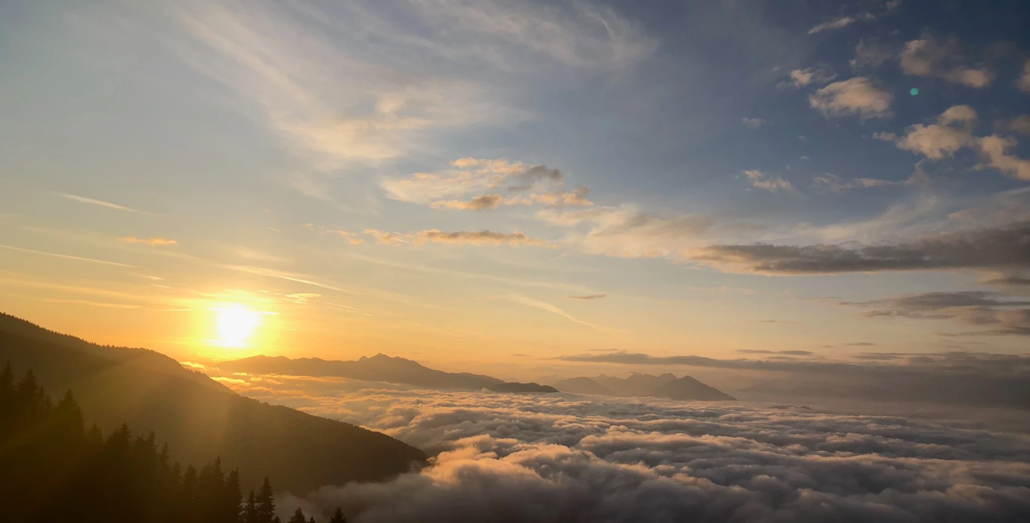 Zonsopkomst boven bergtoppen en een uitgestrekt wolkendek